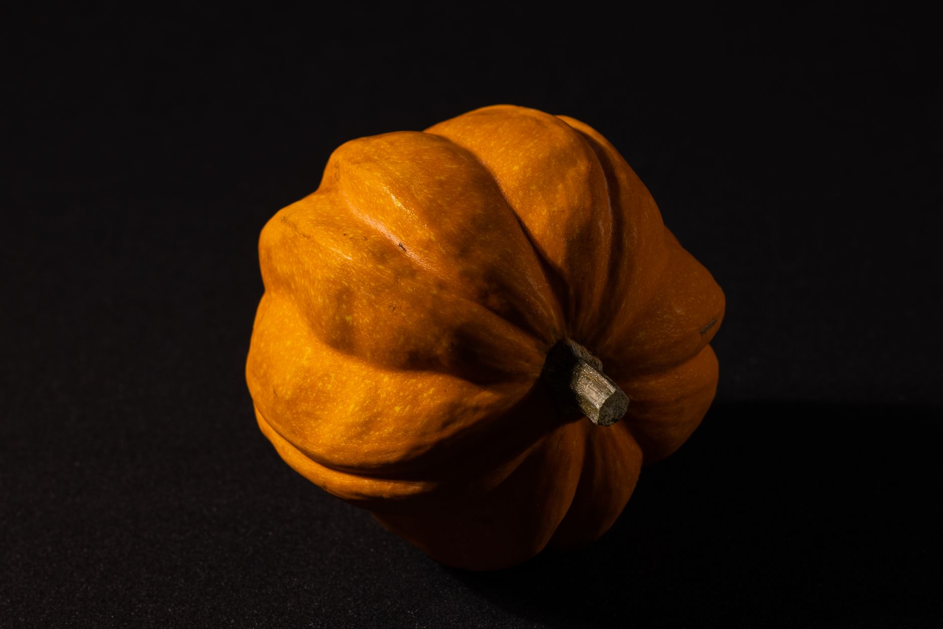 A vivid close-up photo of a pumpkin on a dark background, ideal for seasonal themes.