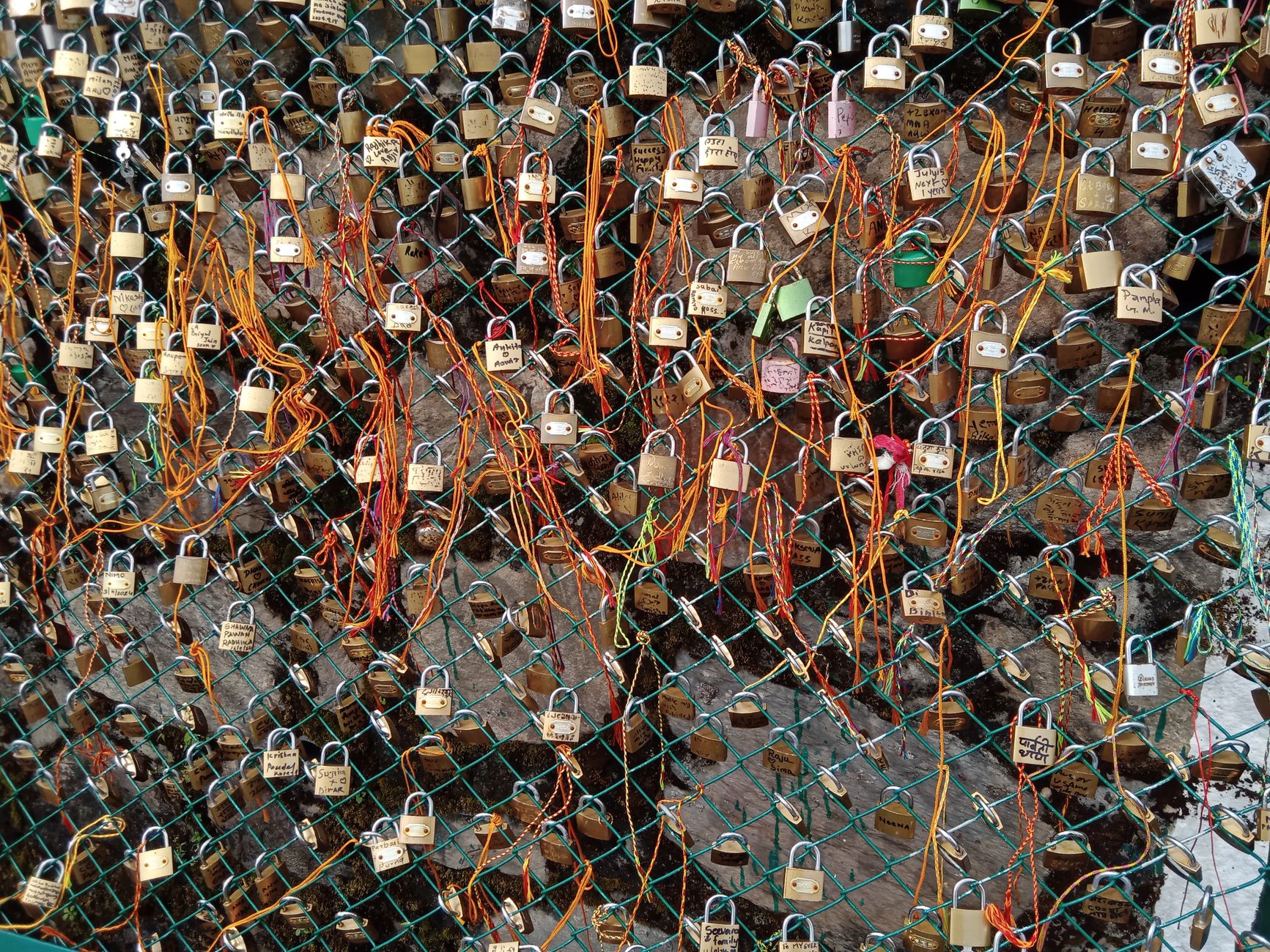 A vibrant display of love locks attached to a fence with colorful ribbons.