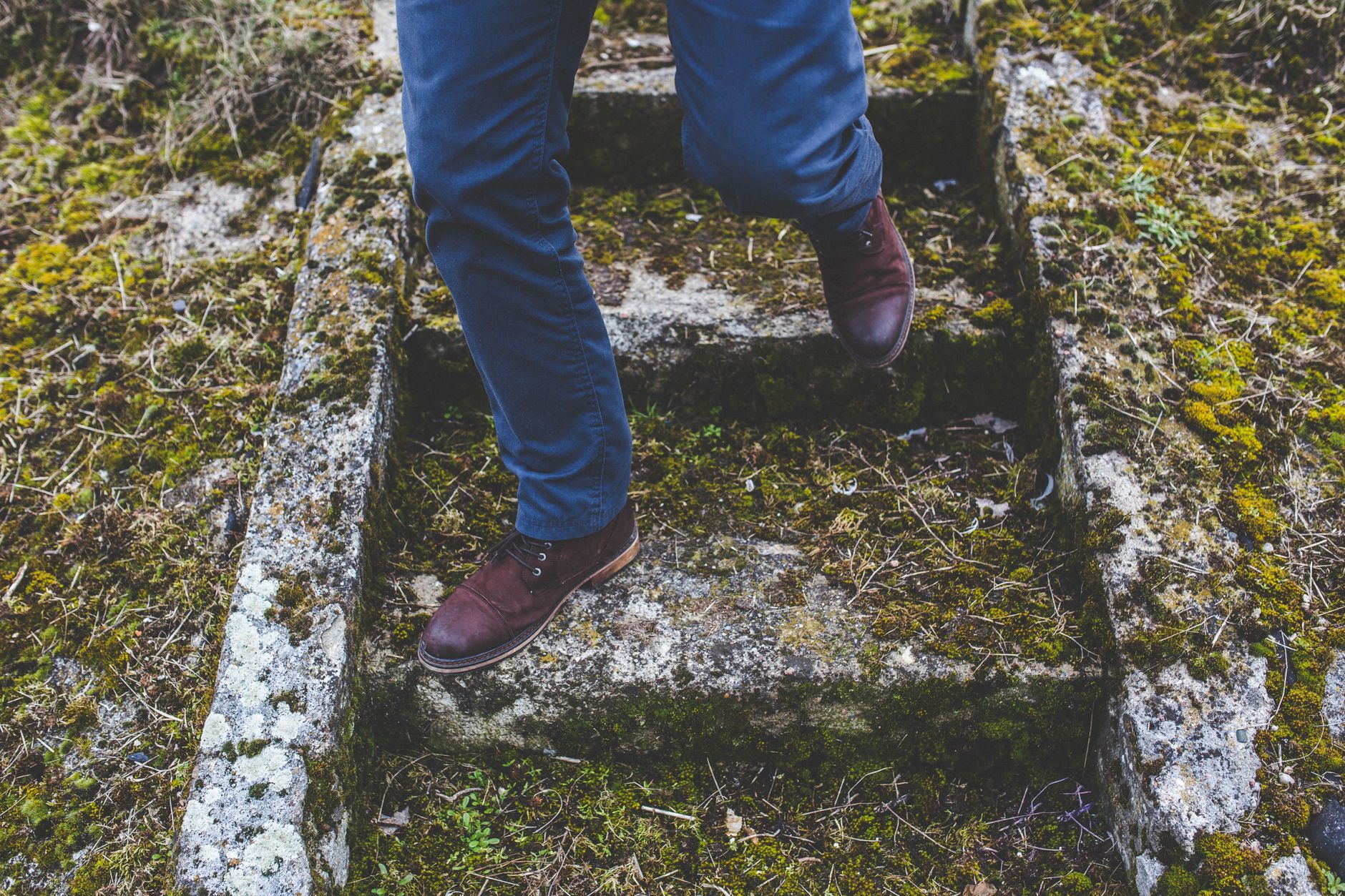 Man stepping down mossy stone steps, showcasing outdoor adventure.
