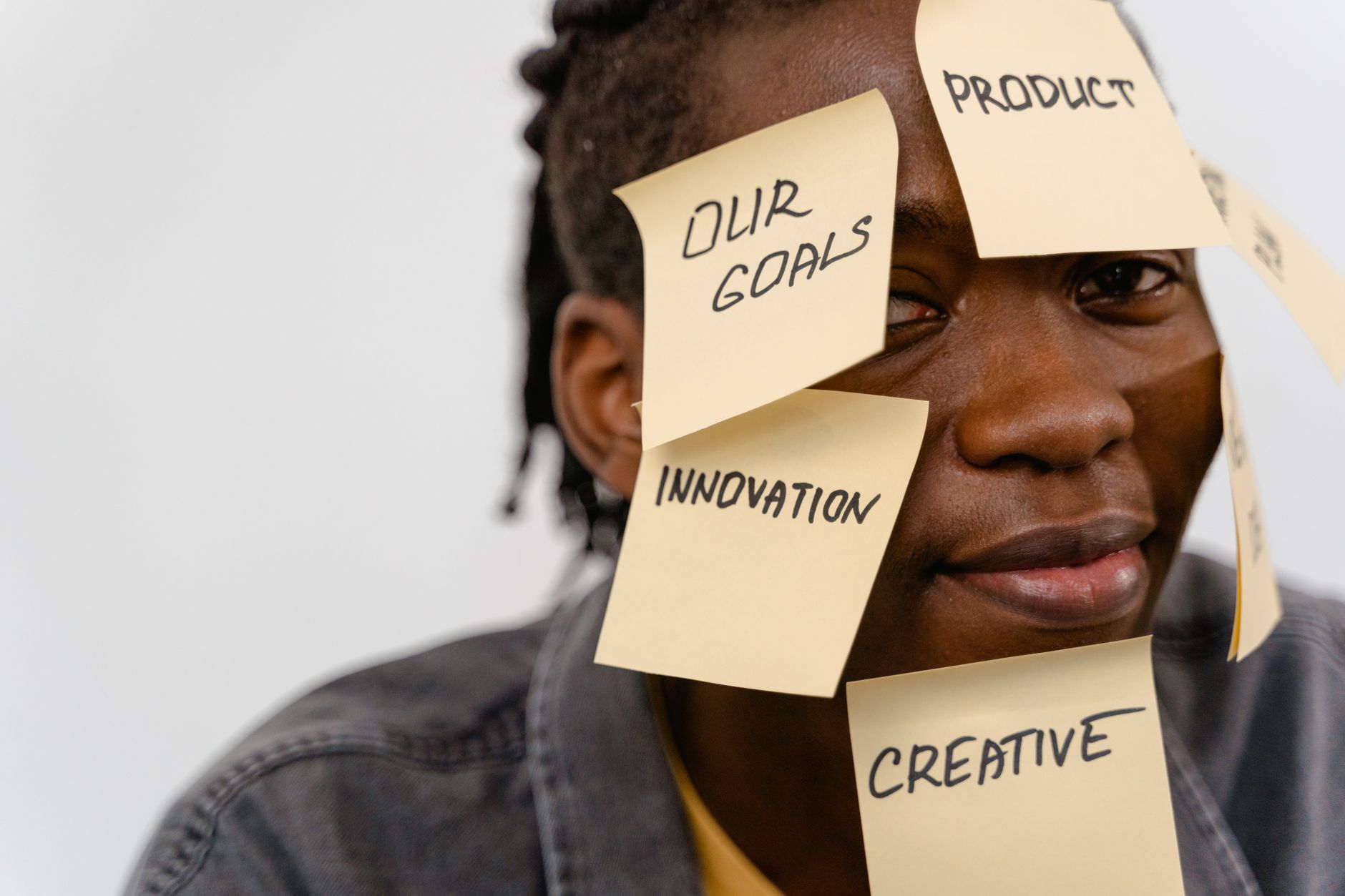 A person with sticky notes on face depicting brainstorming and creative thinking in a studio setting.