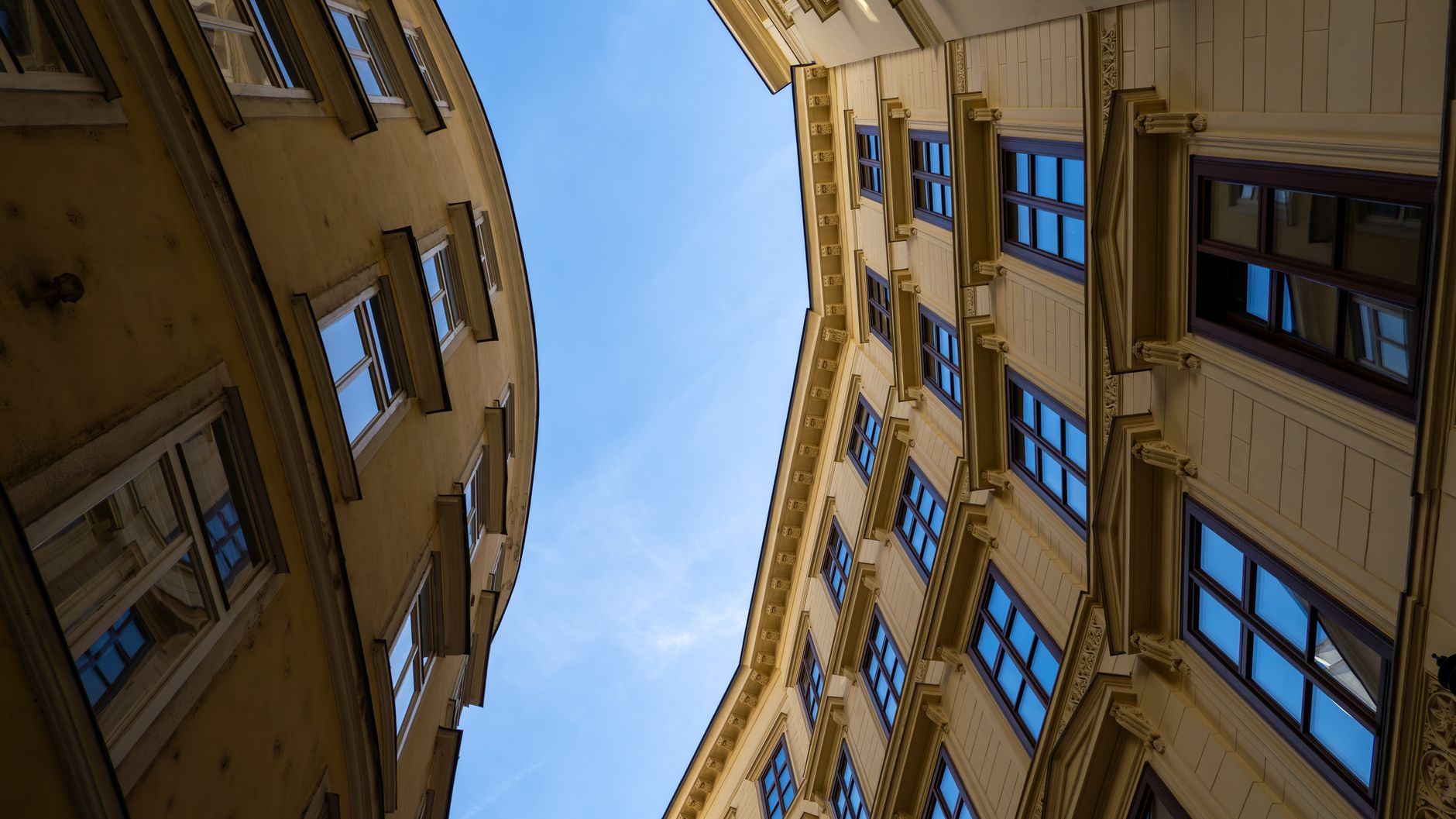 Upward angle view of classic historic buildings against a clear blue sky, showcasing urban architecture.
