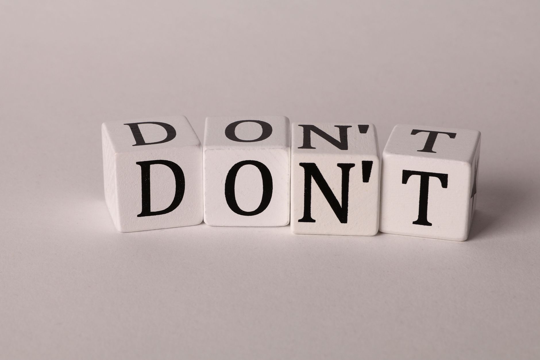 Text cubes spelling 'DON'T' on a clean white background, ideal for concepts of caution or prohibition.