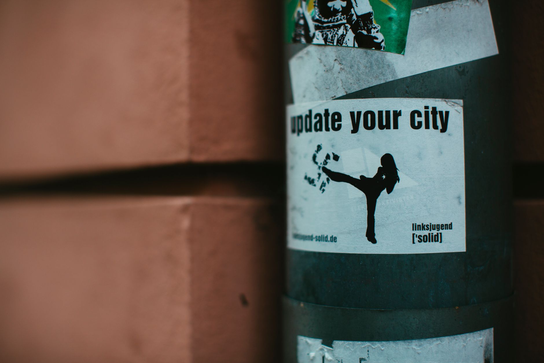 Close-up of urban stickers on a city street pole, highlighting street art and activist themes.