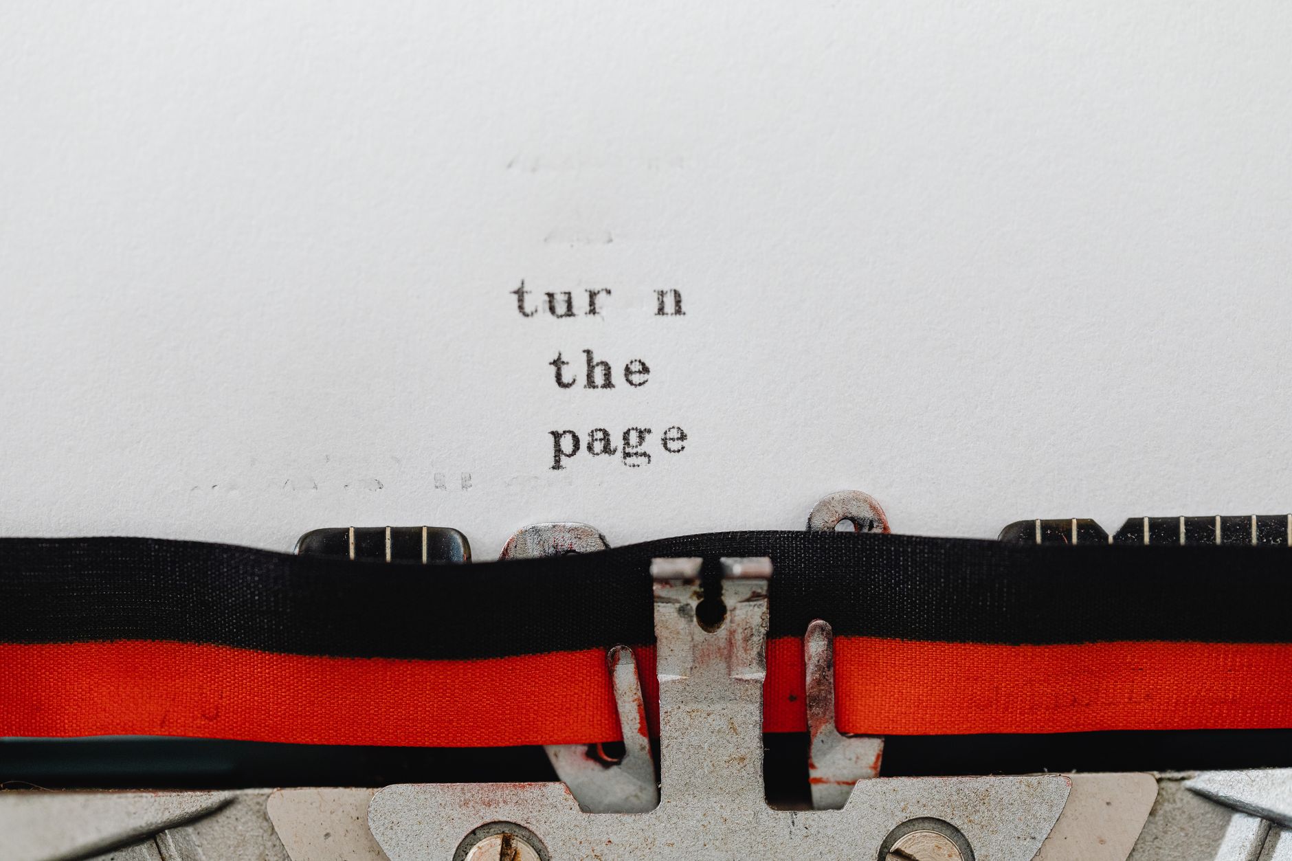 Close-up of a vintage typewriter with text 'turn the page' typed on paper, symbolizing change and new beginnings.